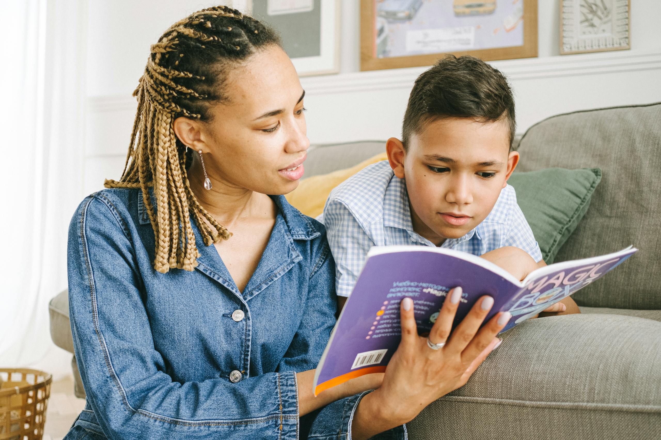 A mother reading a book with her young son on a comfortable couch indoors.