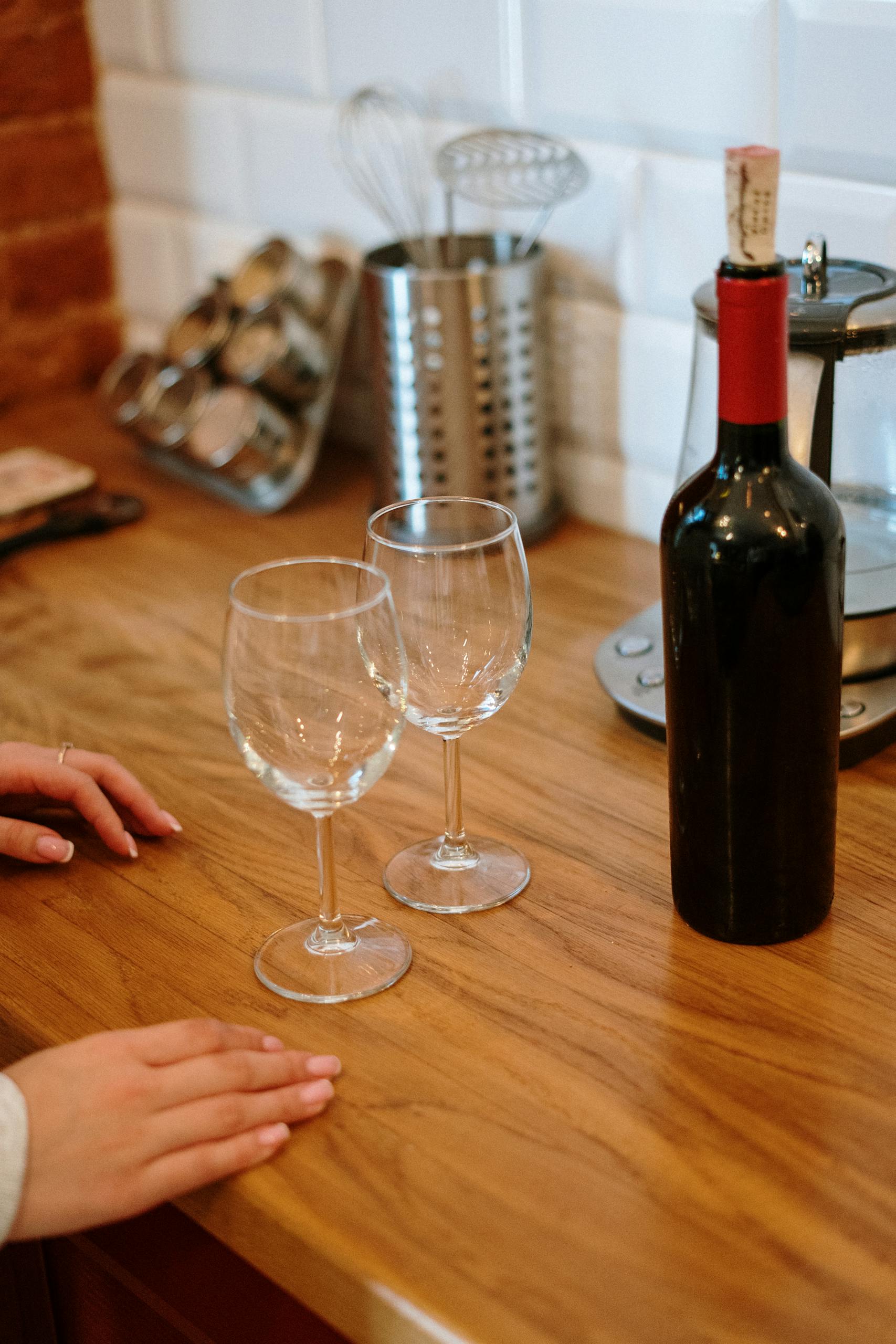 A wooden kitchen counter with a bottle of wine and two wine glasses offering a cozy home atmosphere.